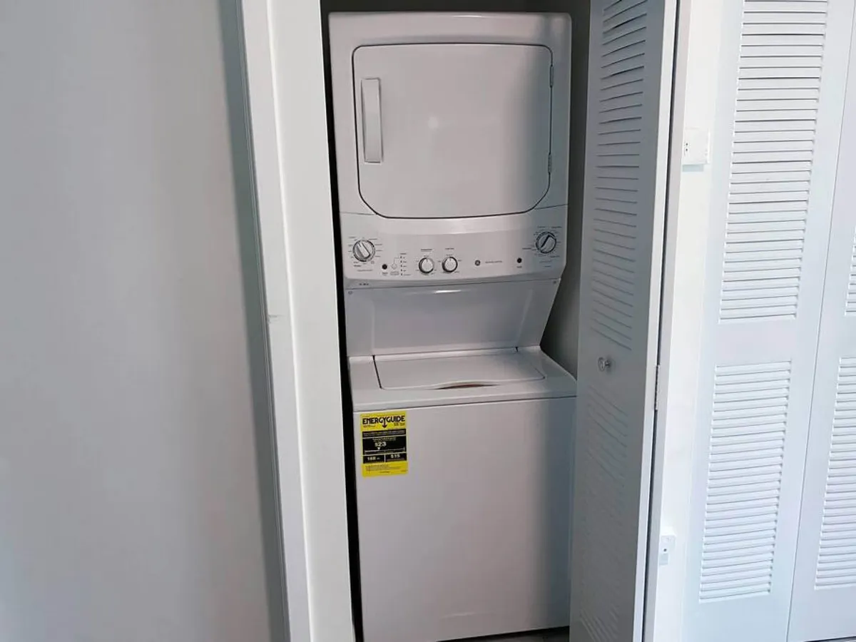 This image shows a stacked washer and dryer neatly situated in a corner of the apartment interior. The area is clean and bright, emphasizing ease of use and practicality for guests who need to do laundry during their stay.